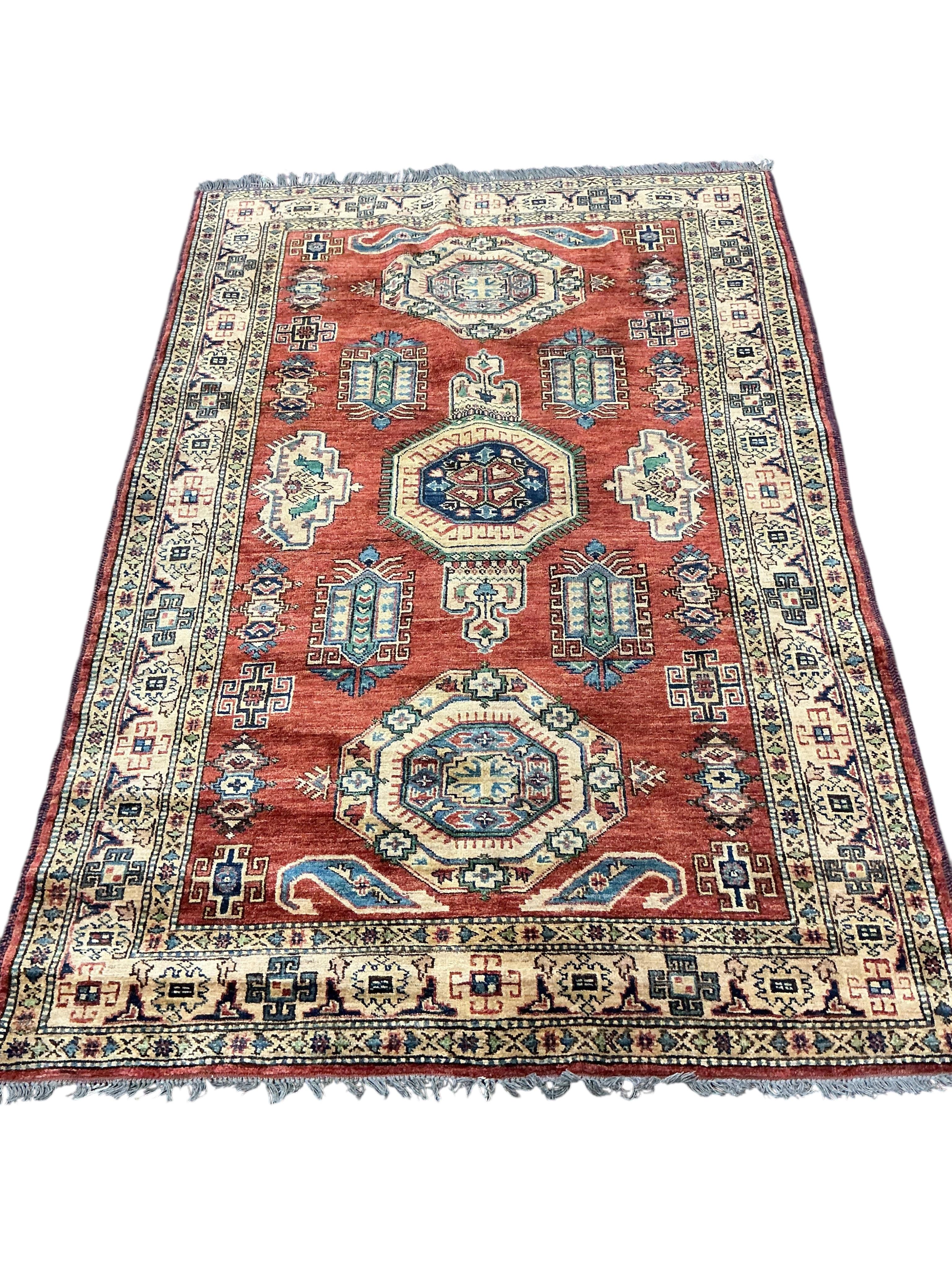 A Caucasian design brick red ground rug, 200cm x 140cm